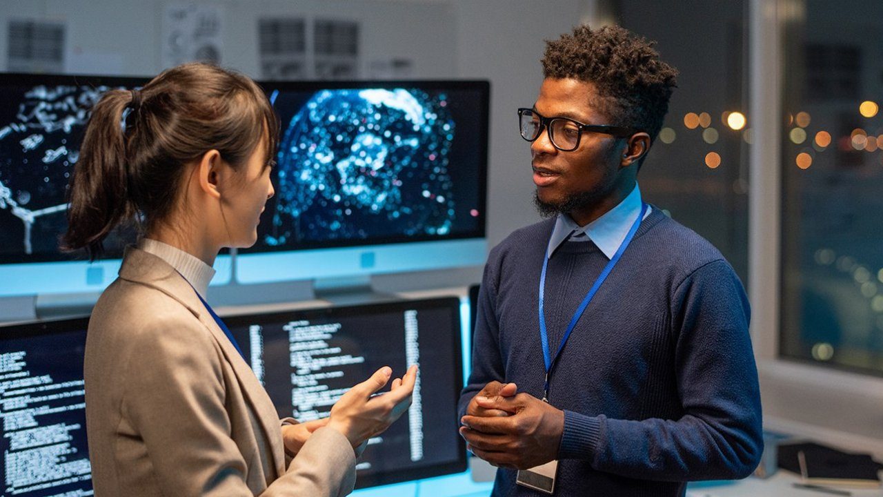 Artificial Intelligence developers discussing a project in front of computer monitors