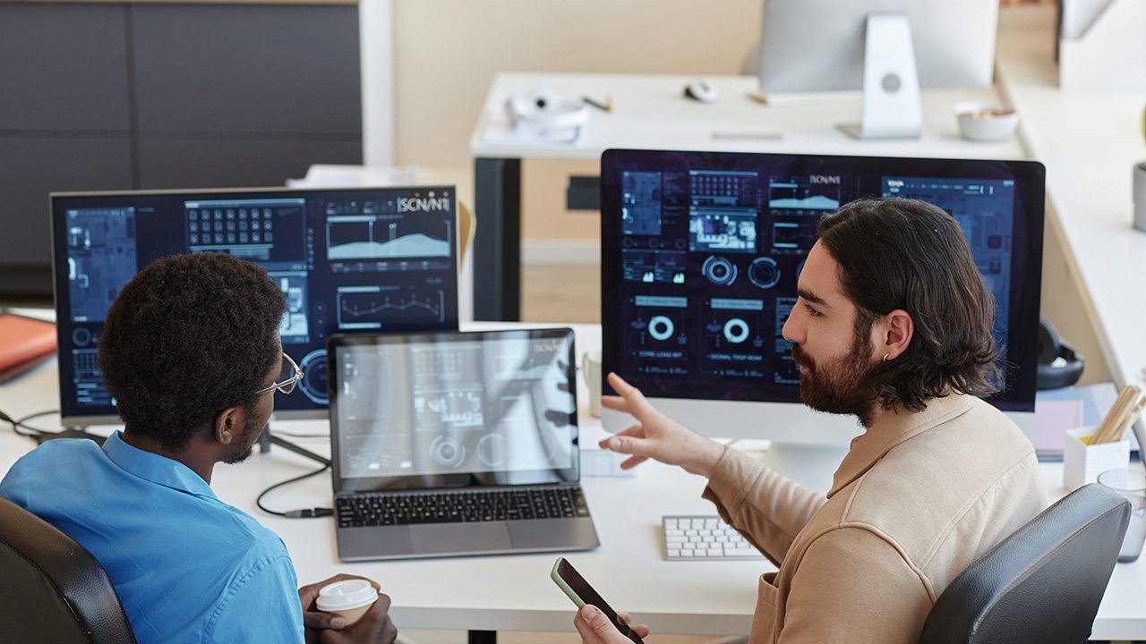 Two Artificial Intelligence developers talking by laptops and computers